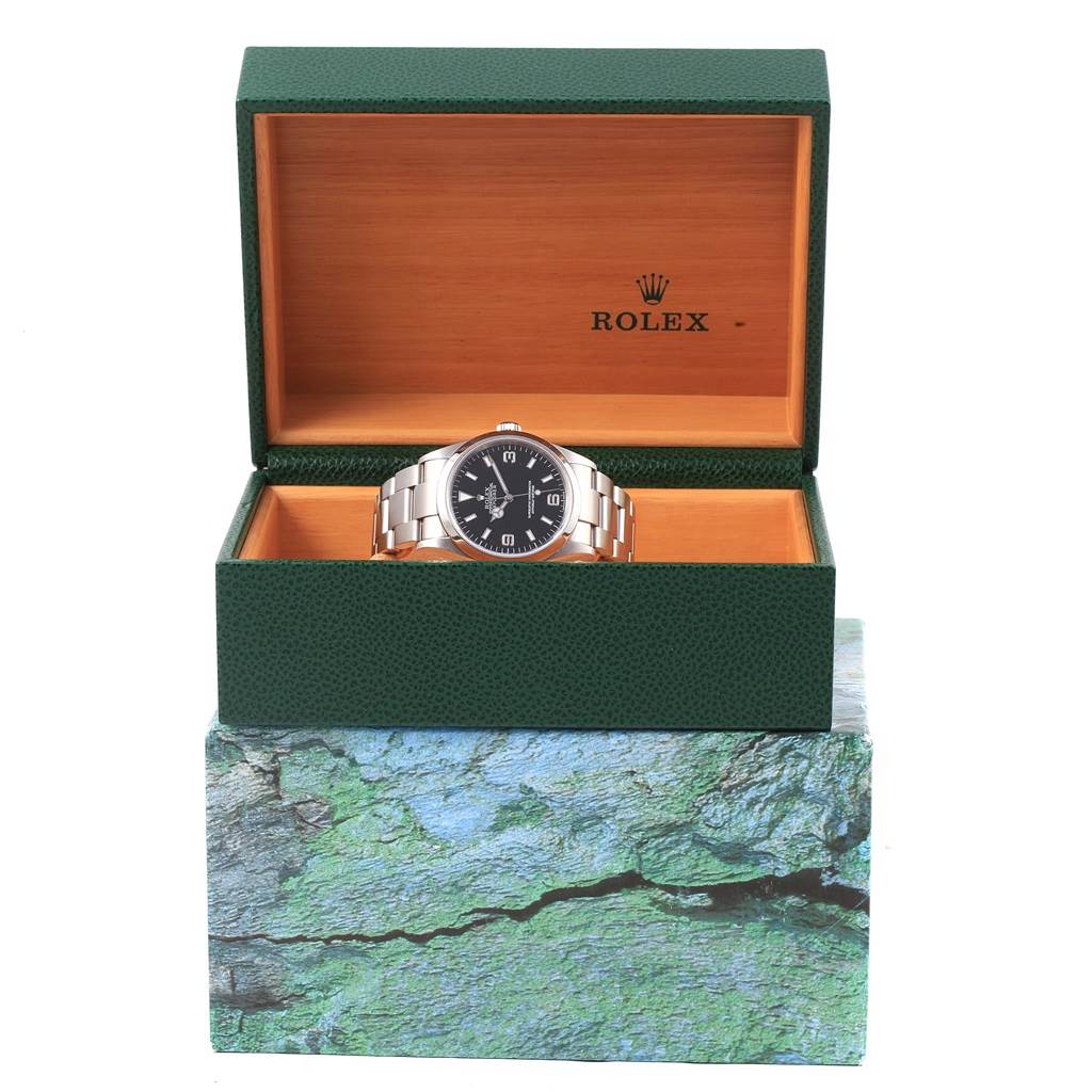 The image shows a Rolex Explorer 114270 Men's Stainless Steel Black Dial 114270 Men's Stainless Steel Black Dial watch front-on, placed inside its open green and wooden Rolex box.
