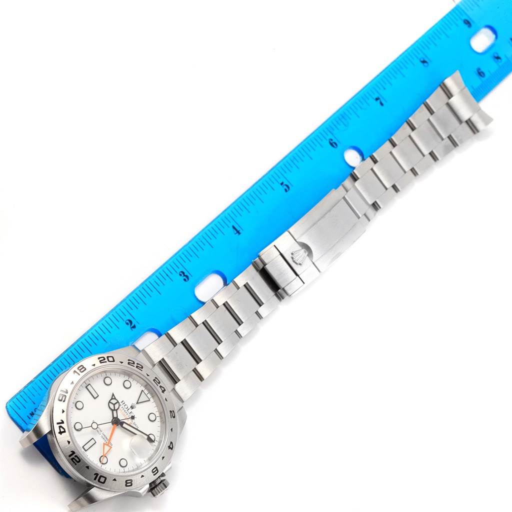 The image shows the front view of a Rolex Explorer 216570 Men's Stainless Steel White Dial 216570 Men's Stainless Steel White Dial watch with its bracelet and a blue ruler for scale.