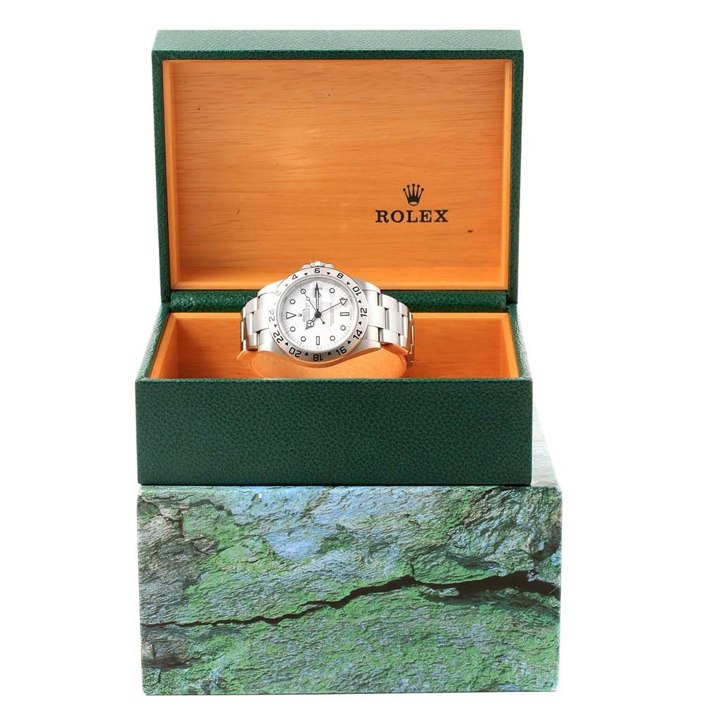The Explorer model by Rolex is shown inside its open green box, displayed from the front angle.