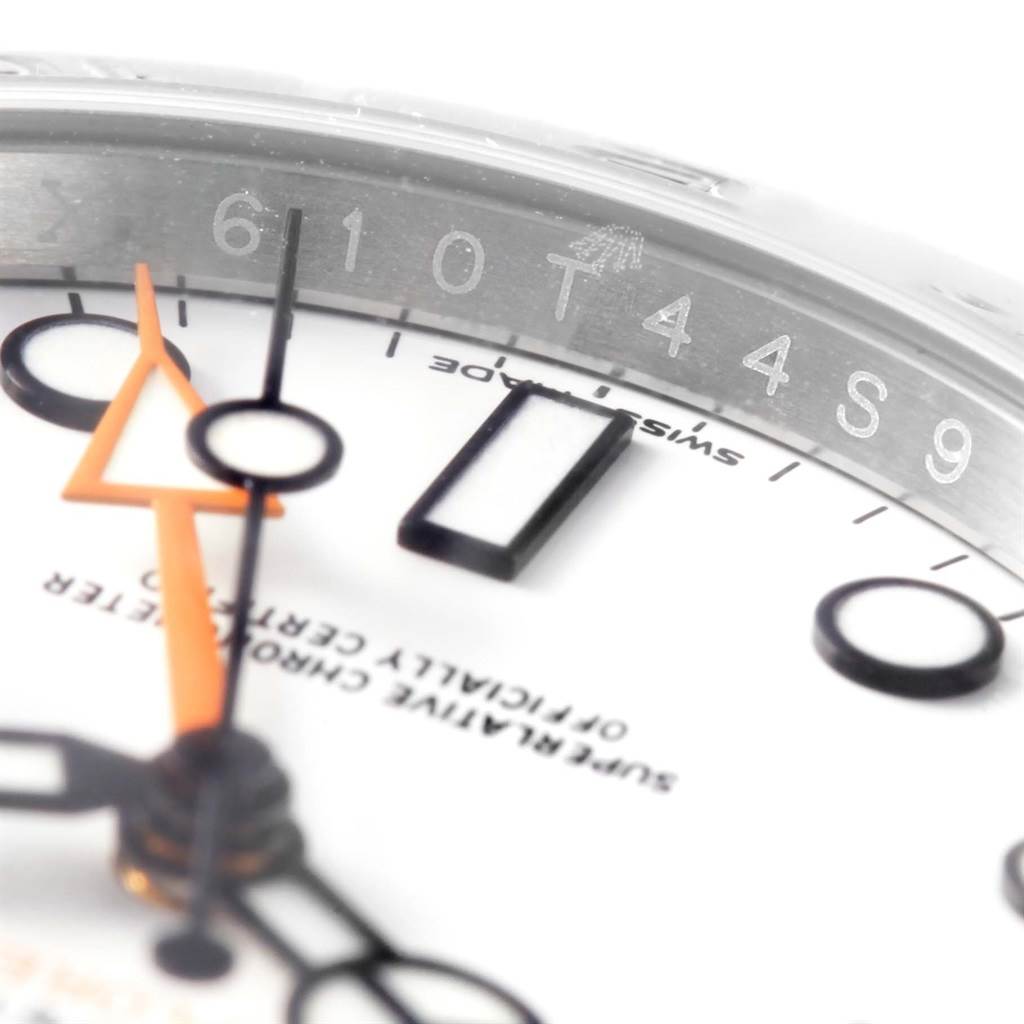 This close-up of a Rolex Explorer 216570 Men's Stainless Steel White Dial 216570 Men's Stainless Steel White Dial watch shows part of the dial, hands, and engraved rehaut.