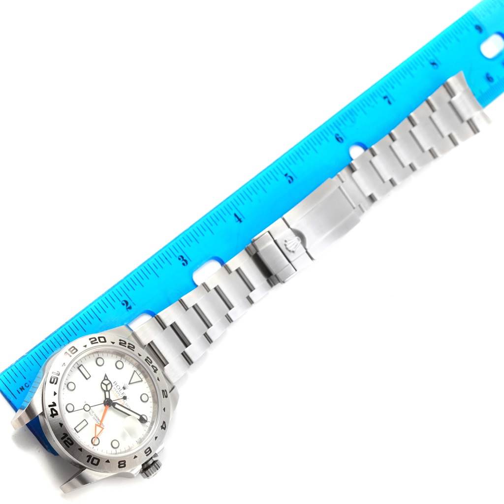 The image shows the front of a Rolex Explorer 216570 Men's Stainless Steel White Dial 216570 Men's Stainless Steel White Dial watch, including the dial, bezel, and bracelet, alongside a ruler for size reference.