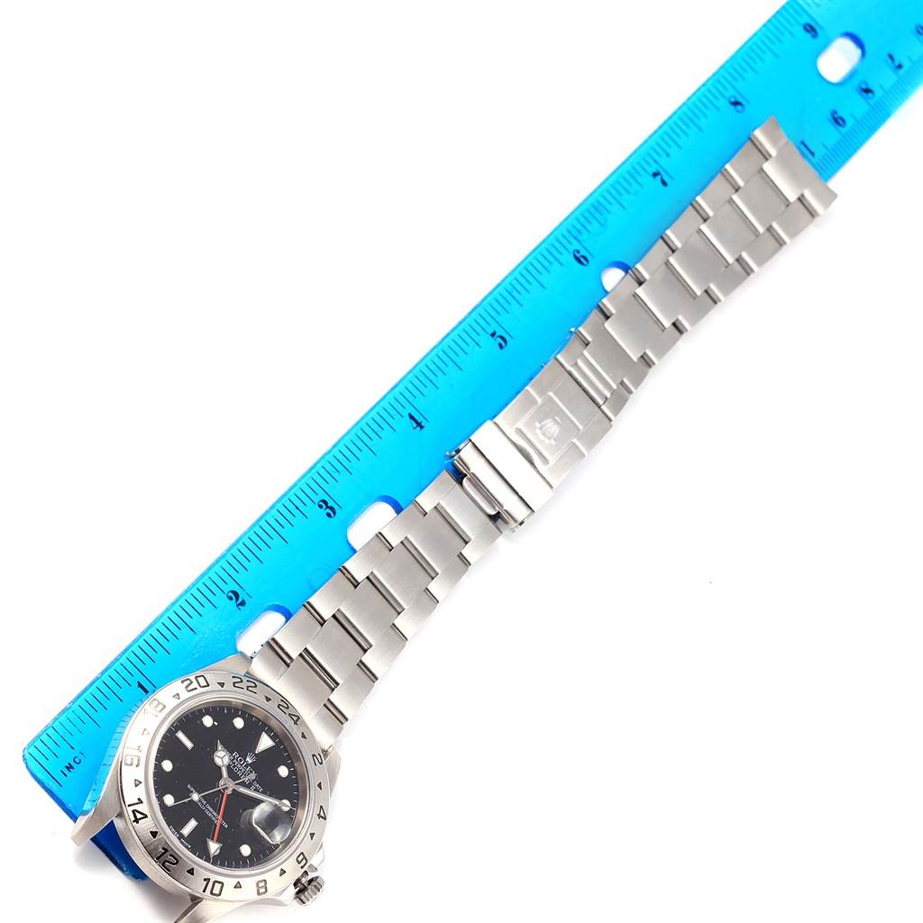 The image shows a top-down view of a Rolex Explorer 16570 Men's Stainless Steel Black Dial 16570 Men's Stainless Steel Black Dial watch, focusing on the face, bezel, and metal band next to a ruler.