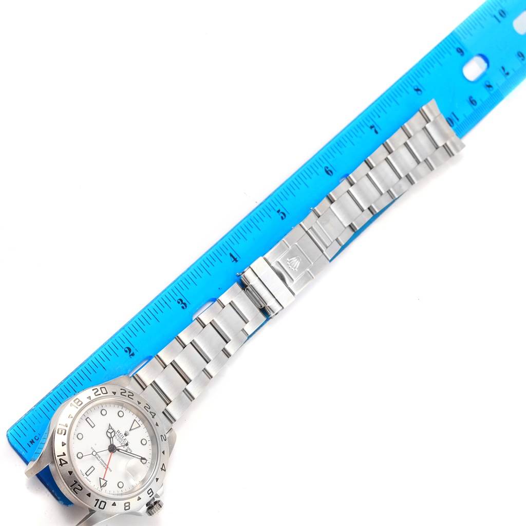 The image shows a Rolex Explorer 16570 Men's Stainless Steel White Dial 16570 Men's Stainless Steel White Dial watch laid flat next to a ruler, highlighting the face, bezel, and bracelet.