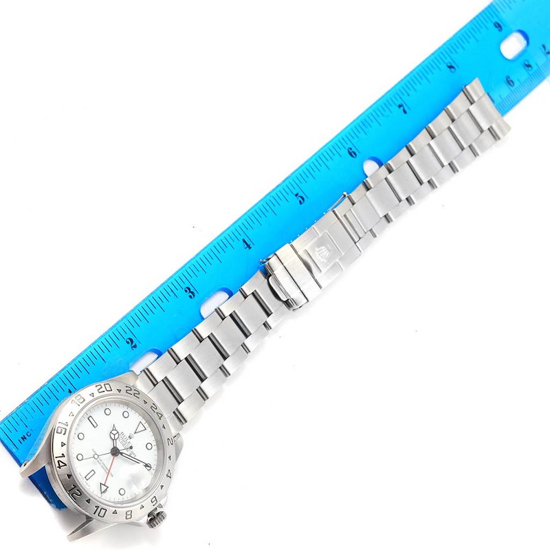 This image shows a Rolex Explorer 16570 Men's Stainless Steel White Dial 16570 Men's Stainless Steel White Dial watch laid flat alongside a blue ruler, highlighting the face and stainless steel bracelet.