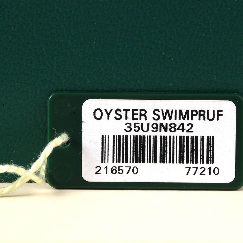 The image shows a close-up of a Rolex Explorer 216570 Men's Stainless Steel White Dial 216570 Men's Stainless Steel White Dial model tag with "OYSTER SWIMPRUF" and a barcode.