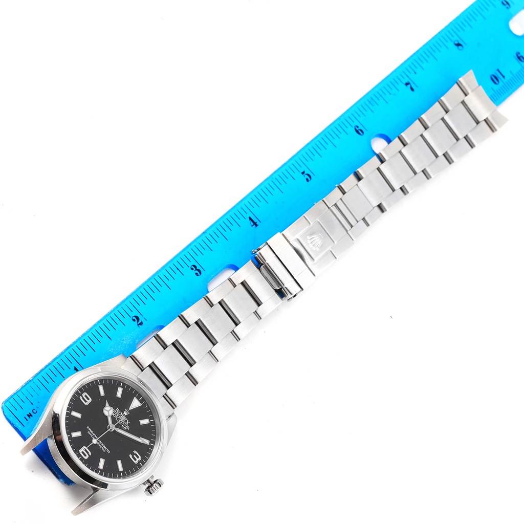 The image shows a Rolex Explorer 114270 Men's Stainless Steel Black Dial 114270 Men's Stainless Steel Black Dial watch laid flat next to a blue ruler, displaying the entire watch and bracelet.