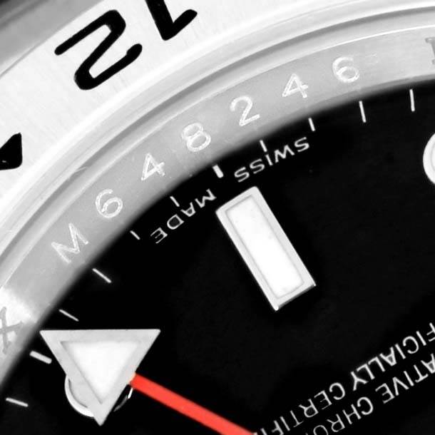 This close-up image of the Rolex Explorer 16570 Men's Stainless Steel Black Dial 16570 Men's Stainless Steel Black Dial watch shows the dial, partial bezel, numerals, and the red-colored GMT hand.