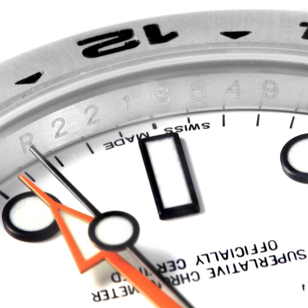 The close-up image of the Rolex Explorer 216570 Men's Stainless Steel White Dial 216570 Men's Stainless Steel White Dial watch shows part of the bezel, dial, and hands, including the seconds hand with an orange arrow tip.