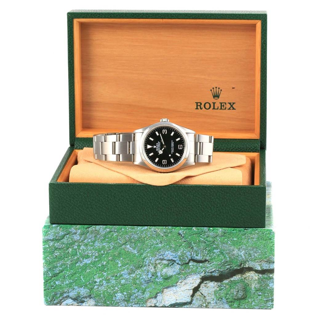 The image shows a Rolex Explorer 14270 Men's Stainless Steel Black Dial 14270 Men's Stainless Steel Black Dial watch displayed inside its open green and wooden Rolex box, resting on a cushion within.