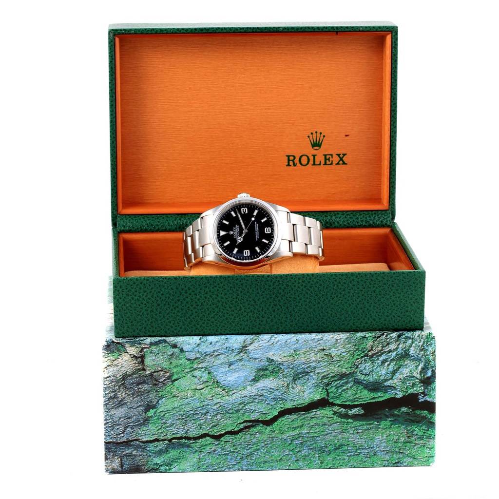 The Rolex Explorer 114270 Men's Stainless Steel Black Dial 114270 Men's Stainless Steel Black Dial watch is shown from the front inside an open Rolex box.
