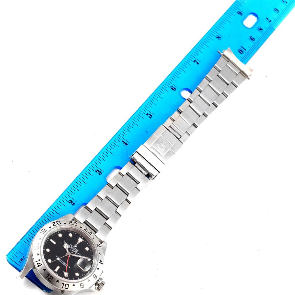 The image shows the Rolex Explorer 16570 Men's Stainless Steel Black Dial 16570 Men's Stainless Steel Black Dial watch laid flat alongside a blue ruler, highlighting its band and face from a top-down angle.