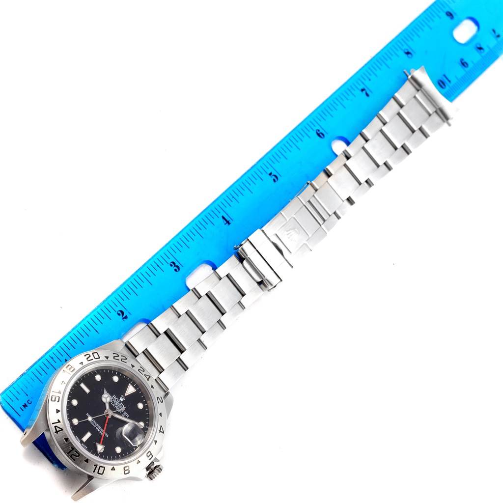 The image shows the Rolex Explorer 16570 Men's Stainless Steel Black Dial 16570 Men's Stainless Steel Black Dial model watch including its face, bezel, crown, and metal bracelet, placed alongside a blue ruler.