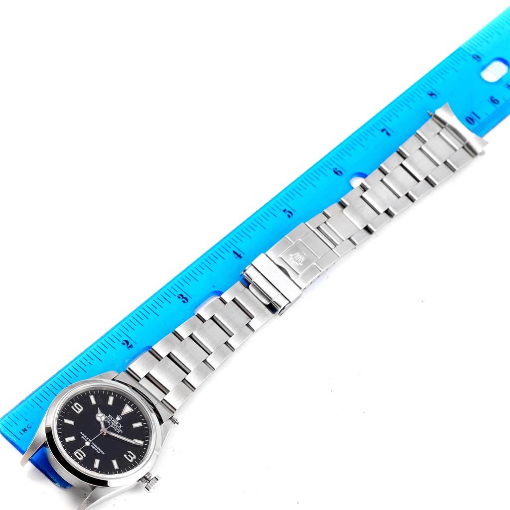 The Rolex Explorer 14270 Men's Stainless Steel Black Dial 14270 Men's Stainless Steel Black Dial watch is shown from a top-down angle, with the full bracelet and clasp displayed alongside a ruler.