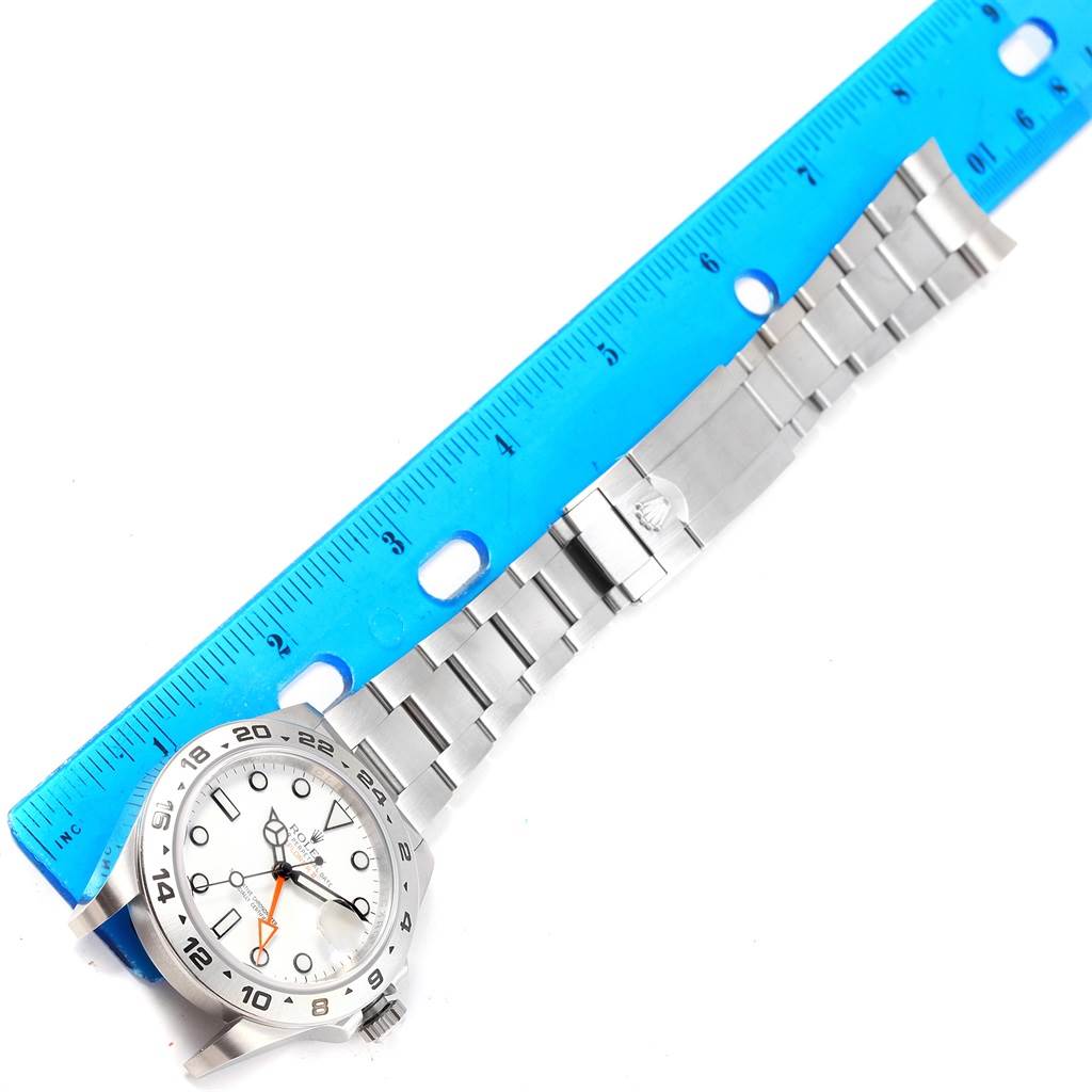 The image shows a Rolex Explorer 216570 Men's Stainless Steel White Dial 216570 Men's Stainless Steel White Dial watch laid flat with a blue ruler beside it for scale.