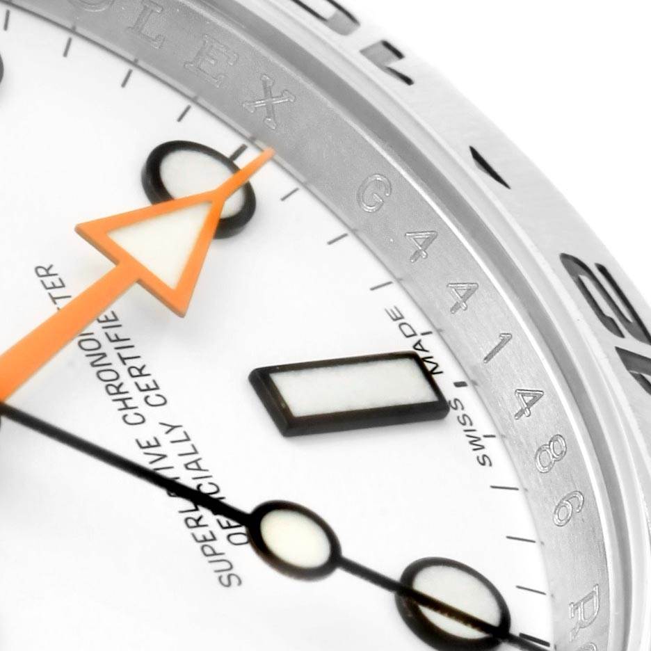 Close-up of the dial and bezel of a Rolex Explorer 216570 Men's Stainless Steel White Dial 216570 Men's Stainless Steel White Dial, showing the orange hour hand, markers, and part of the engraved bezel.