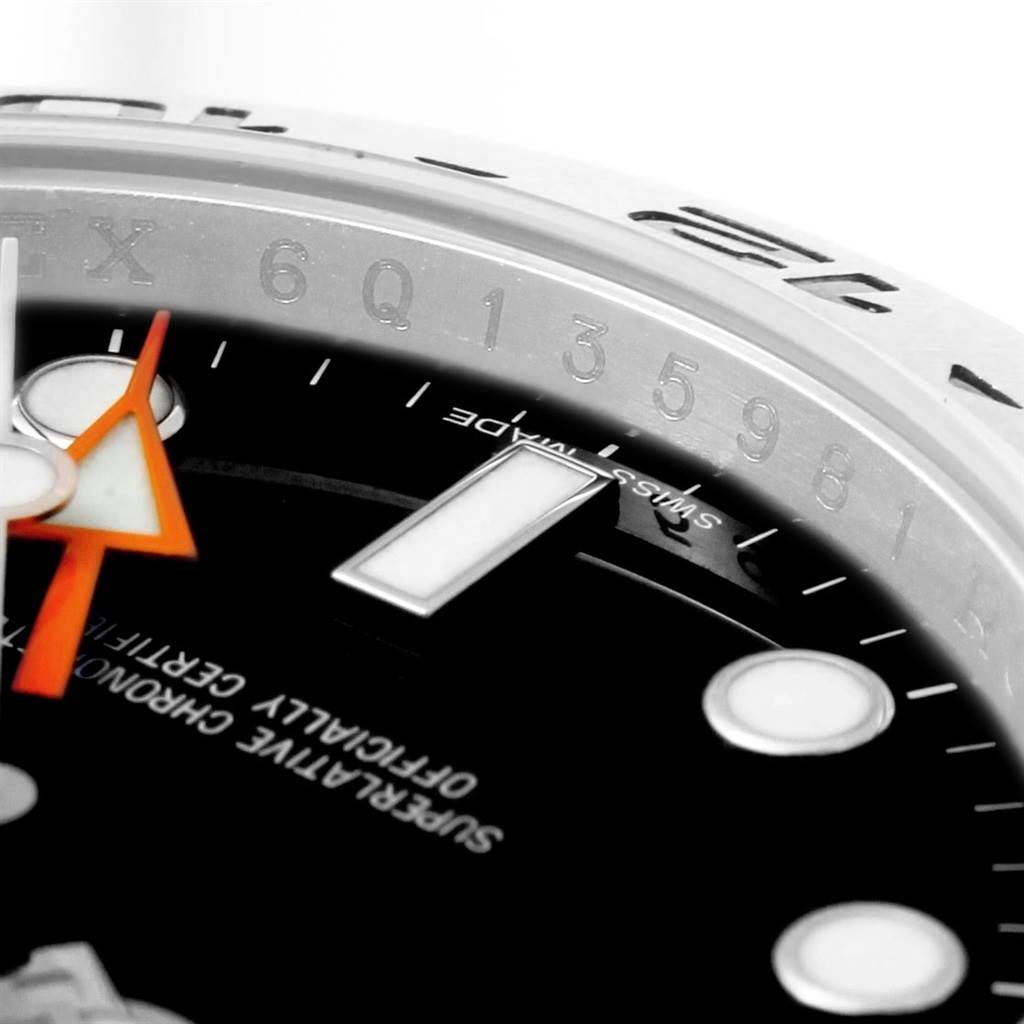This close-up of a Rolex Explorer 216570 Men's Stainless Steel Black Dial 216570 Men's Stainless Steel Black Dial watch shows part of the dial, indices, and bezel from an angle.