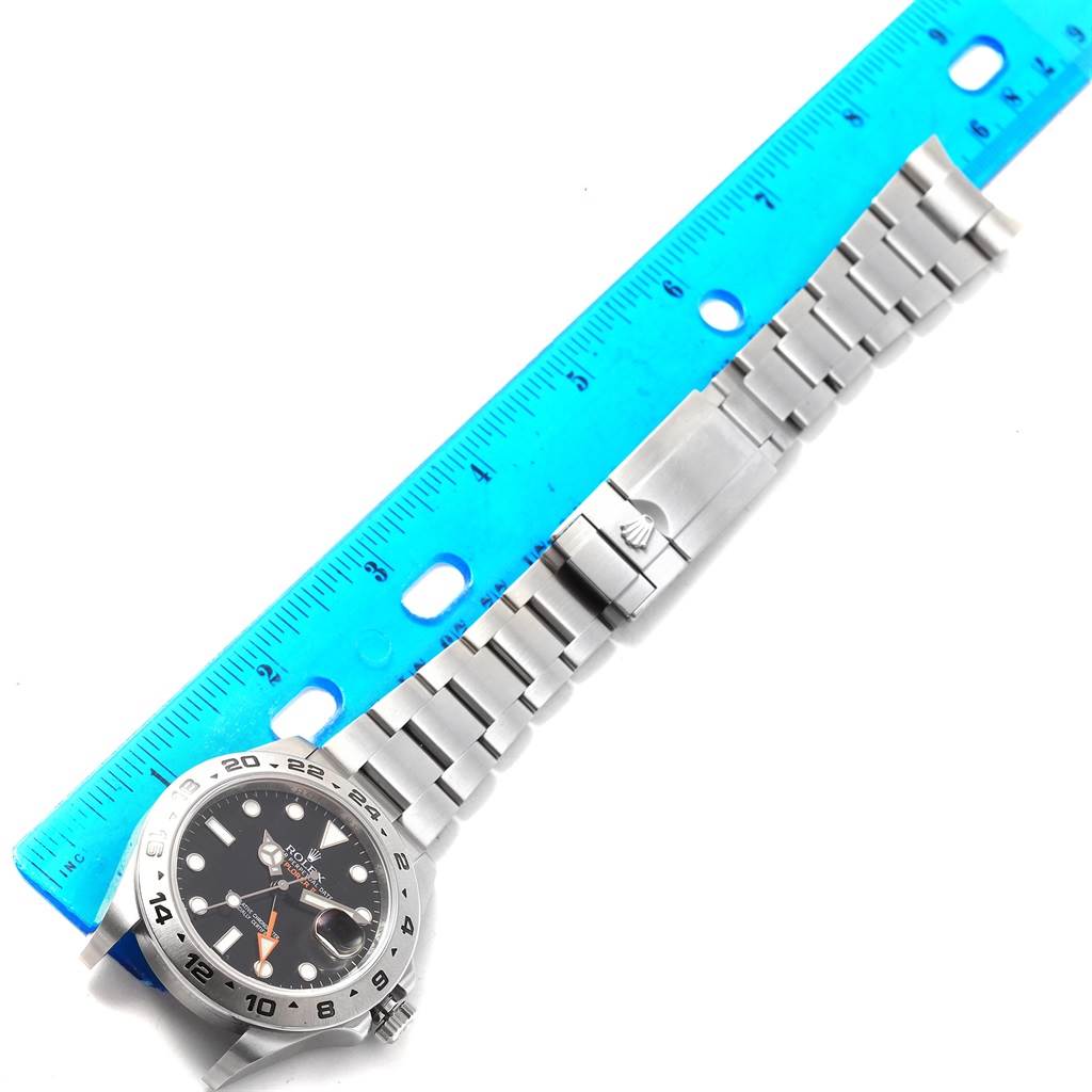 The Rolex Explorer 216570 Men's Stainless Steel Black Dial 216570 Men's Stainless Steel Black Dial watch is shown from an overhead angle along with its metal bracelet and a blue ruler for scale.