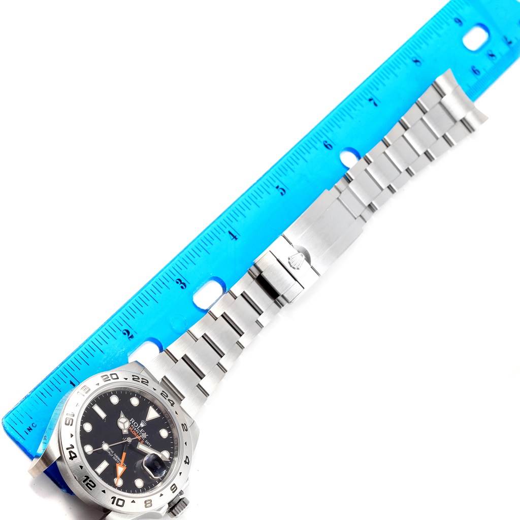 The image shows a top view of a Rolex Explorer 216570 Men's Stainless Steel Black Dial 216570 Men's Stainless Steel Black Dial watch with its bracelet measured against a blue ruler.