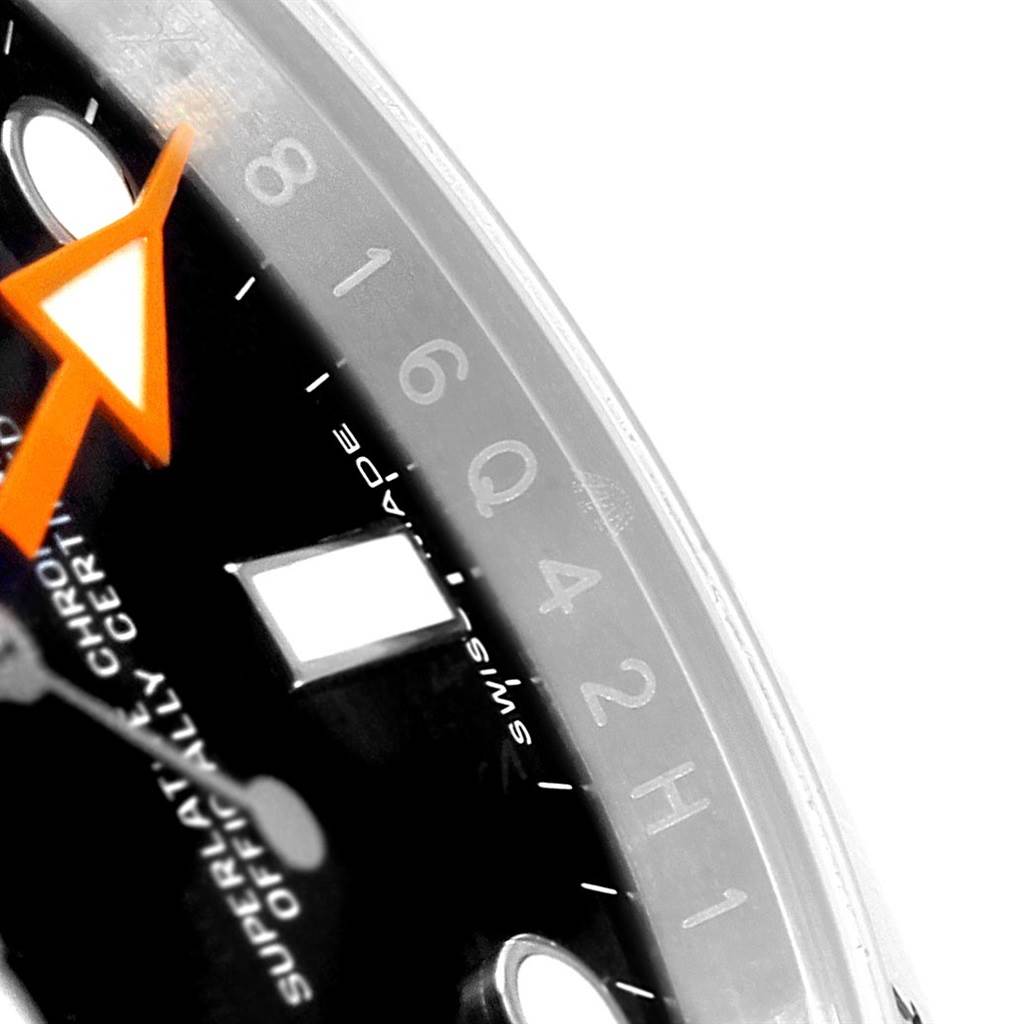 The close-up image of the Rolex Explorer 216570 Men's Stainless Steel Black Dial 216570 Men's Stainless Steel Black Dial watch shows the dial and part of the bezel, highlighting the orange hand and some numeral markings.