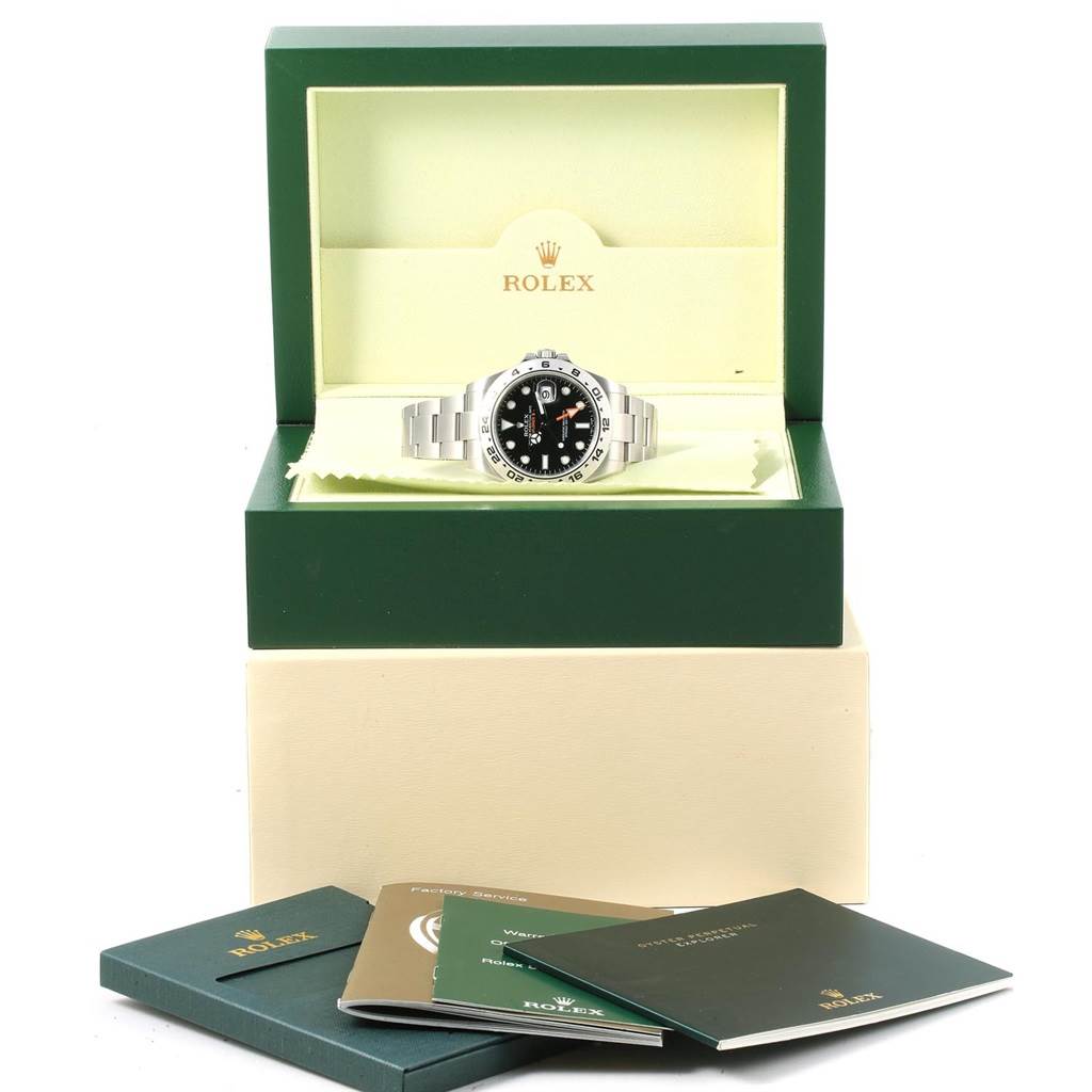 The Rolex Explorer 216570 Men's Stainless Steel Black Dial 216570 Men's Stainless Steel Black Dial watch is displayed inside its open box with accompanying booklets in the foreground.