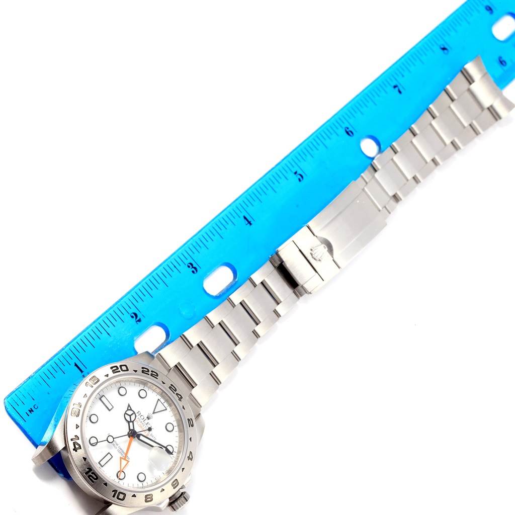 This image shows a top-down view of a Rolex Explorer 216570 Men's Stainless Steel White Dial 216570 Men's Stainless Steel White Dial watch alongside a blue ruler for size reference.