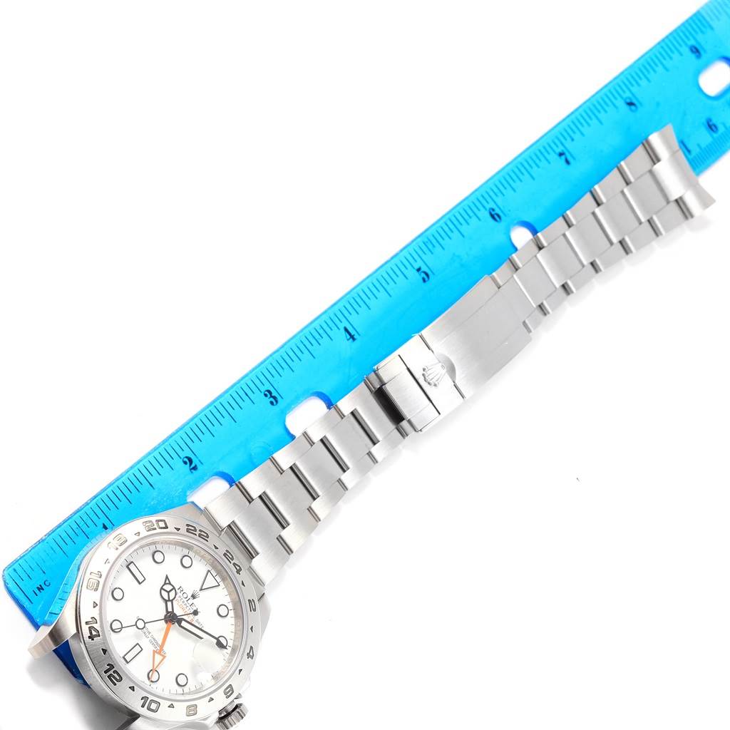 The image shows a Rolex Explorer 216570 Men's Stainless Steel White Dial 216570 Men's Stainless Steel White Dial watch laid next to a ruler, highlighting the face and metal bracelet of the watch.