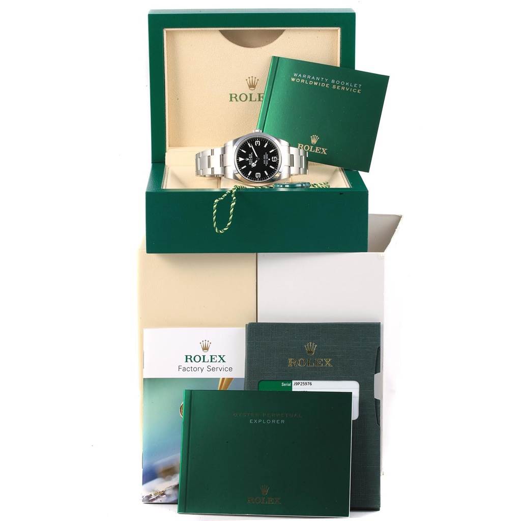 The image shows a front angle of a Rolex Explorer 214270 Men's Stainless Steel Black Dial 214270 Men's Stainless Steel Black Dial watch with its box, warranty booklets, and service papers.