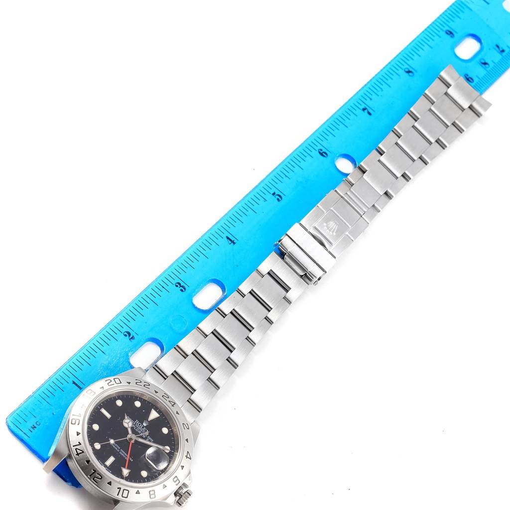 The image shows a top-down view of a Rolex Explorer 16570 Men's Stainless Steel Black Dial 16570 Men's Stainless Steel Black Dial watch, including its face, bezel, and bracelet, alongside a ruler for scale.