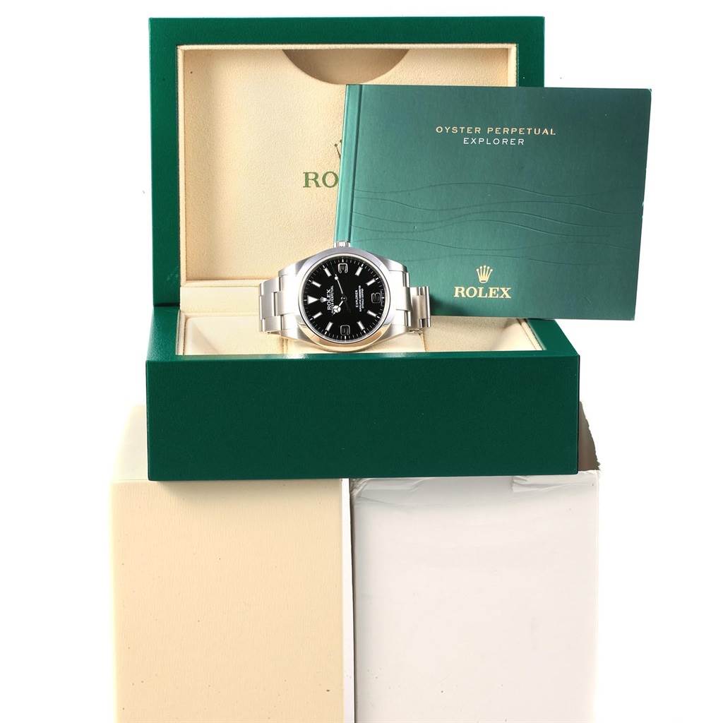 A Rolex Explorer 214270 Men's Stainless Steel Black Dial 214270 Men's Stainless Steel Black Dial watch is displayed inside its green box at a front angle, accompanied by an Oyster Perpetual Explorer booklet.