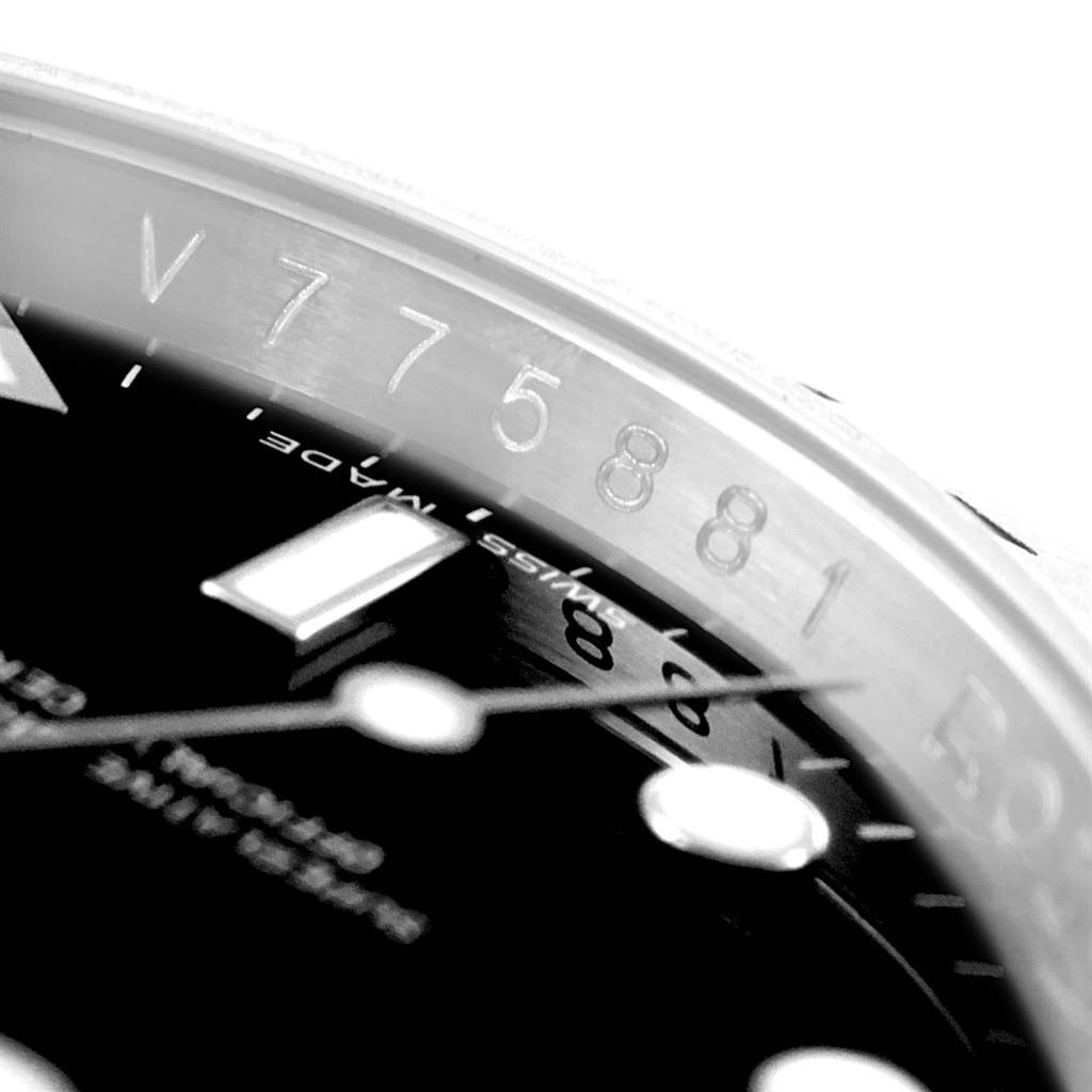 This close-up image of the Rolex Explorer 16570 Men's Stainless Steel Black Dial 16570 Men's Stainless Steel Black Dial watch shows part of the dial, markers, and a segment of the bezel with its serial number.