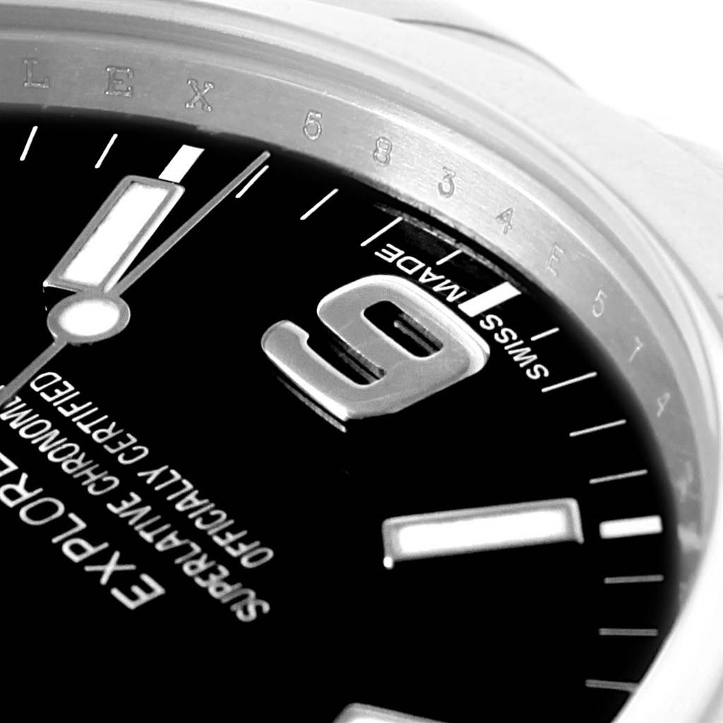 This close-up image of the Rolex Explorer 214270 Men's Stainless Steel Black Dial 214270 Men's Stainless Steel Black Dial model watch showcases its dial, including the 9 o'clock marker and part of the bezel.