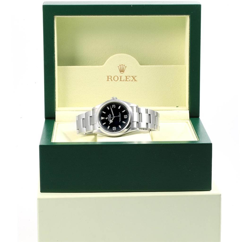 The Rolex Explorer 114270 Men's Stainless Steel Black Dial 114270 Men's Stainless Steel Black Dial watch is presented front-on in its green and cream box, displaying its black dial and stainless steel bracelet.