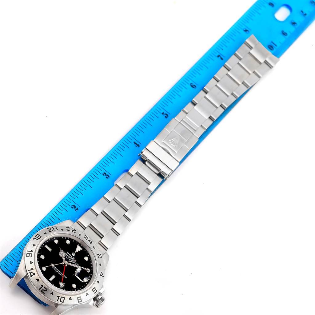 The image shows the Rolex Explorer 16570 Men's Stainless Steel Black Dial 16570 Men's Stainless Steel Black Dial watch laid out flat against a blue ruler, highlighting the bracelet and bezel.