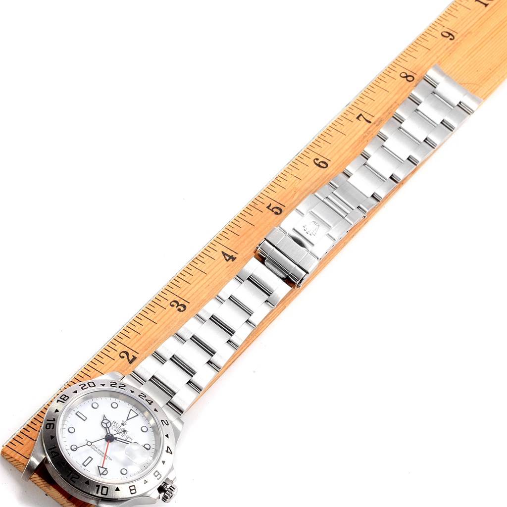 The Rolex Explorer 16570 Men's Stainless Steel White Dial 16570 Men's Stainless Steel White Dial watch is shown at an angle with its dial and bracelet flat alongside a measuring ruler.