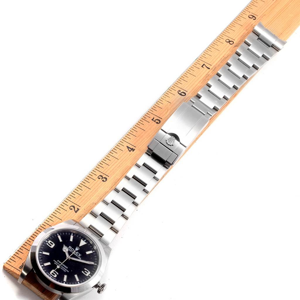 The Rolex Explorer 214270 Men's Stainless Steel Black Dial 214270 Men's Stainless Steel Black Dial watch is shown from a top view, alongside a ruler for size reference.