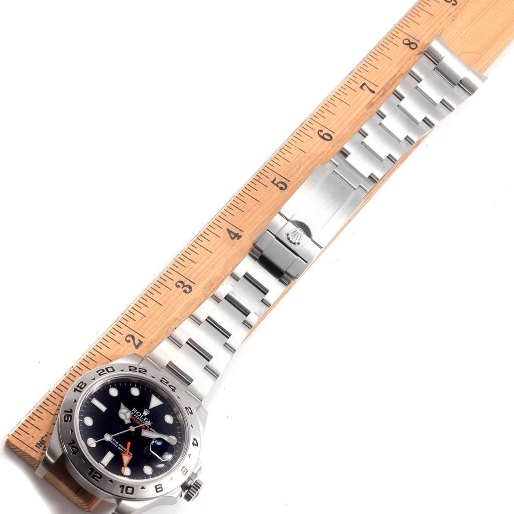 This image shows the Rolex Explorer 216570 Men's Stainless Steel Black Dial 216570 Men's Stainless Steel Black Dial watch laid flat with its full stainless steel bracelet next to a wooden ruler.