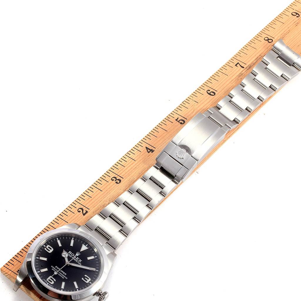 The image shows a Rolex Explorer 214270 Men's Stainless Steel Black Dial 214270 Men's Stainless Steel Black Dial watch laid flat, with the face and stainless steel bracelet aligned next to a ruler.