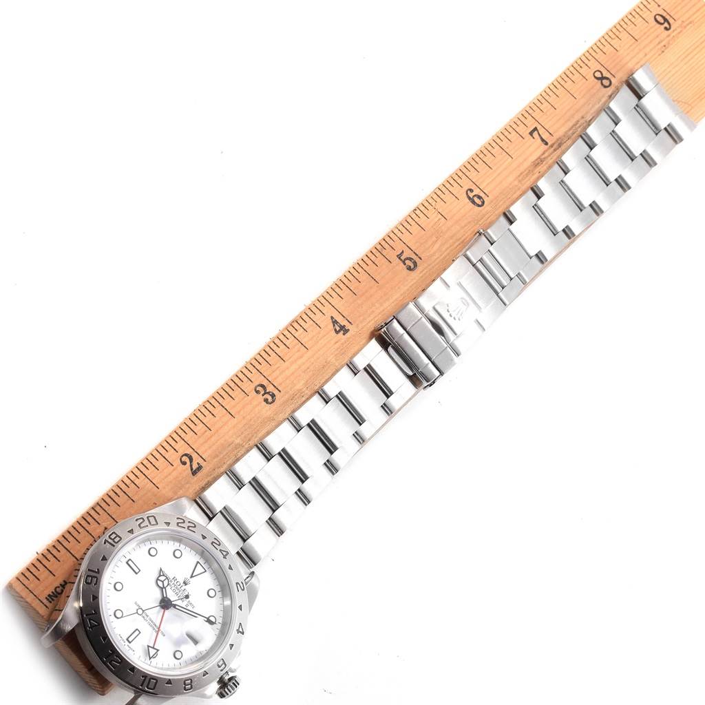 The image shows a Rolex Explorer 16570 Men's Stainless Steel White Dial 16570 Men's Stainless Steel White Dial watch laid flat next to a wooden ruler, highlighting the watch head and stainless steel bracelet.