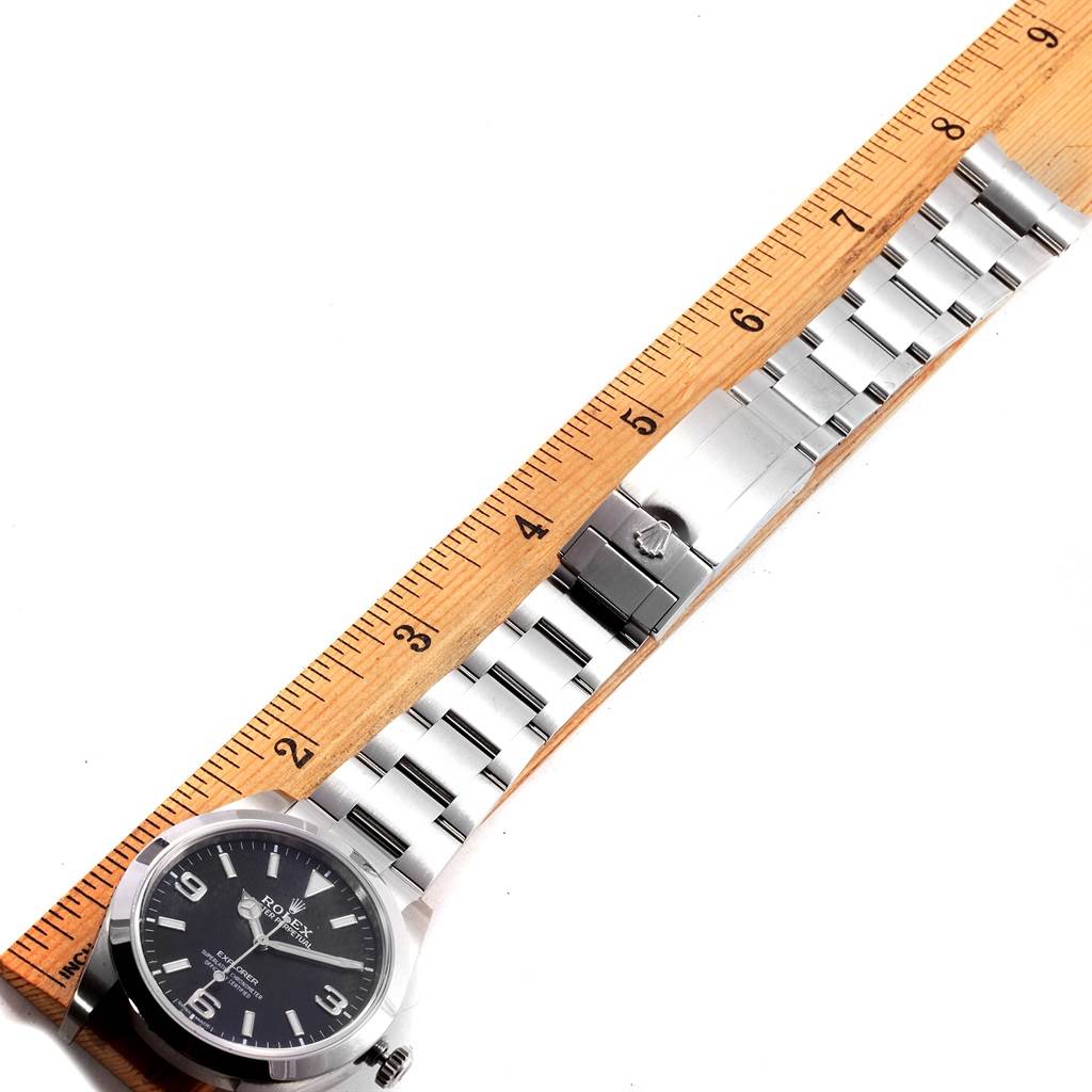 The image shows a Rolex Explorer 214270 Men's Stainless Steel Black Dial 214270 Men's Stainless Steel Black Dial watch laid flat next to a measuring ruler, displaying its dial, bracelet, and clasp.