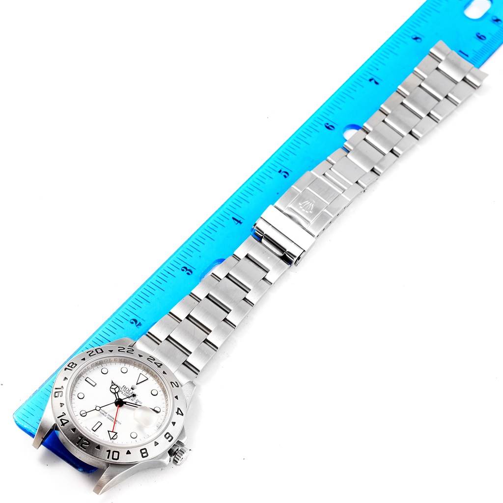 The Rolex Explorer 16570 Men's Stainless Steel White Dial 16570 Men's Stainless Steel White Dial watch is shown from a top view, displaying the watch face, bezel, bracelet, and clasp alongside a ruler for scale.