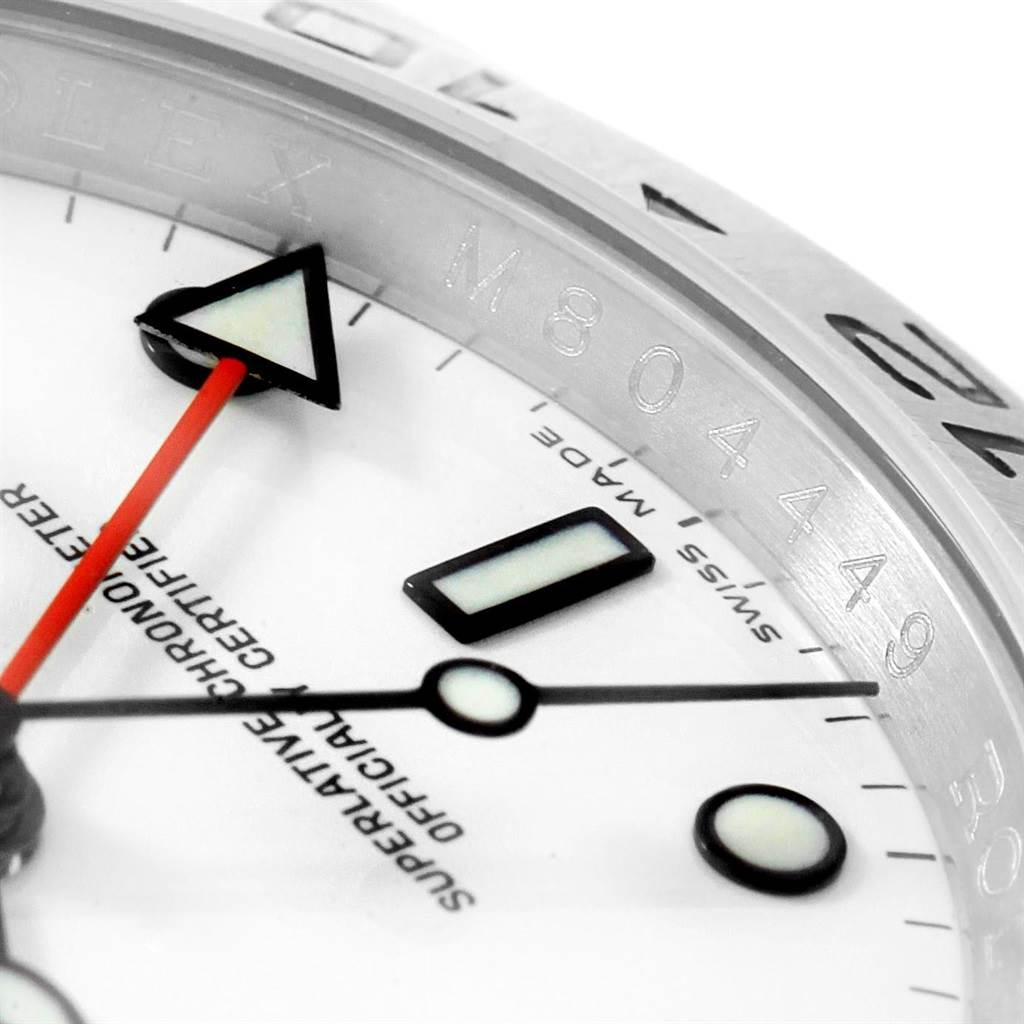 This is a close-up of the Rolex Explorer 16570 Men's Stainless Steel White Dial 16570 Men's Stainless Steel White Dial watch showing part of the dial, hands, and engraved bezel with serial numbers.