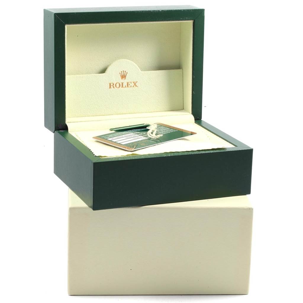 The image shows an open green and beige Rolex box for the Explorer model, containing its warranty card and accessories.
