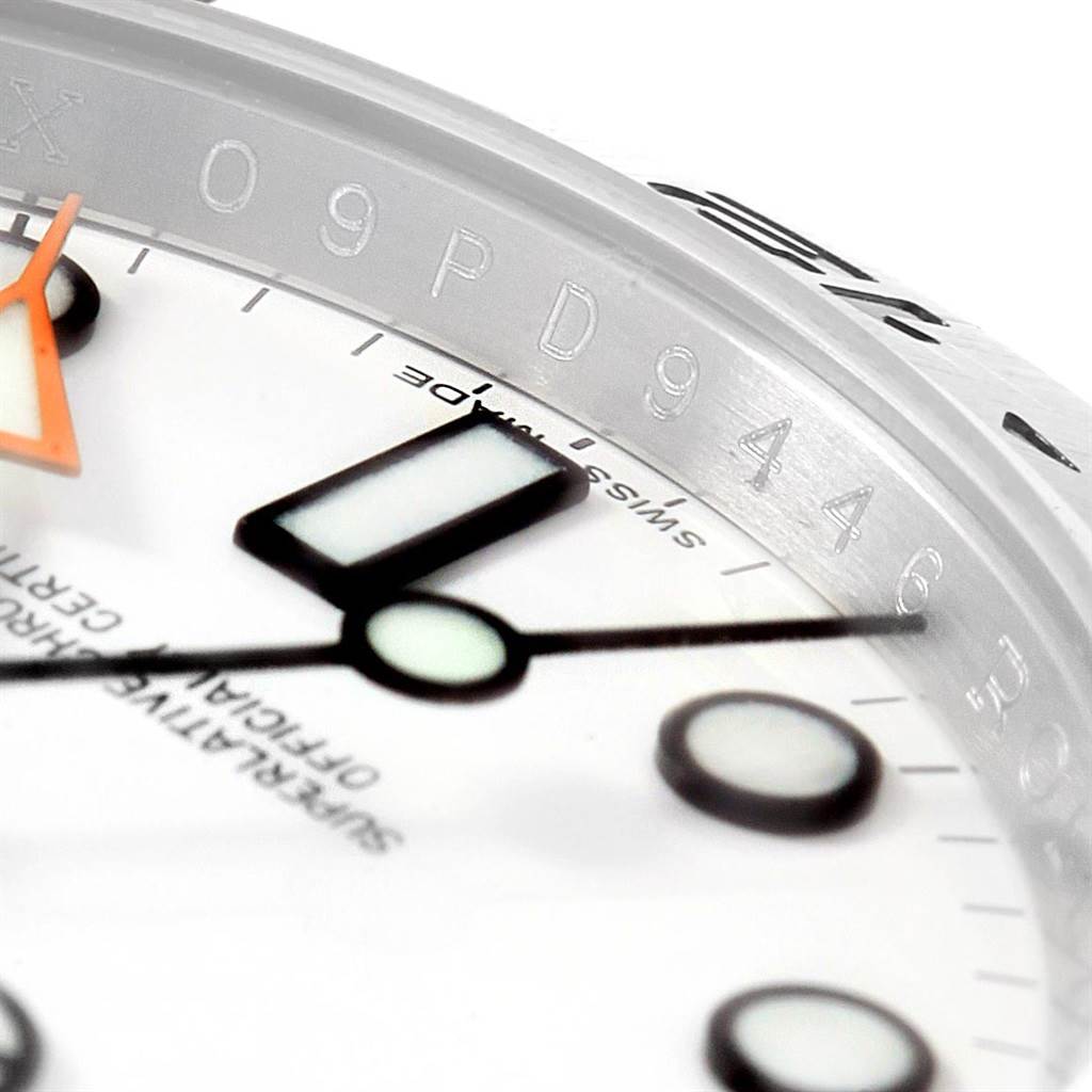 This close-up angle of the Rolex Explorer 216570 Men's Stainless Steel White Dial 216570 Men's Stainless Steel White Dial watch shows the hands, indices, part of the bezel, and engravings on the inner ring.