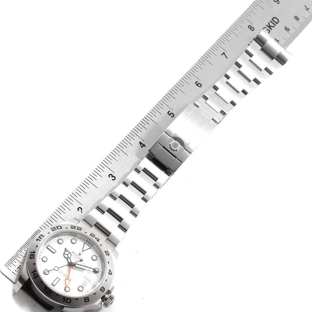 The image shows a top view of a Rolex Explorer 216570 Men's Stainless Steel White Dial 216570 Men's Stainless Steel White Dial watch lying next to a ruler, highlighting its bracelet and clasp.