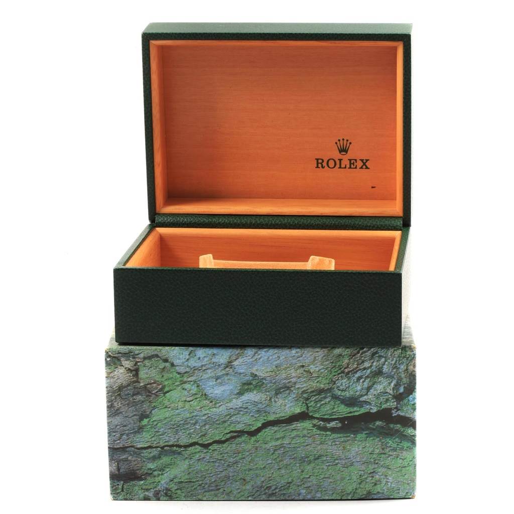 The image shows an open green and wooden Rolex watch box for the Explorer model, placed on a decorative outer box.