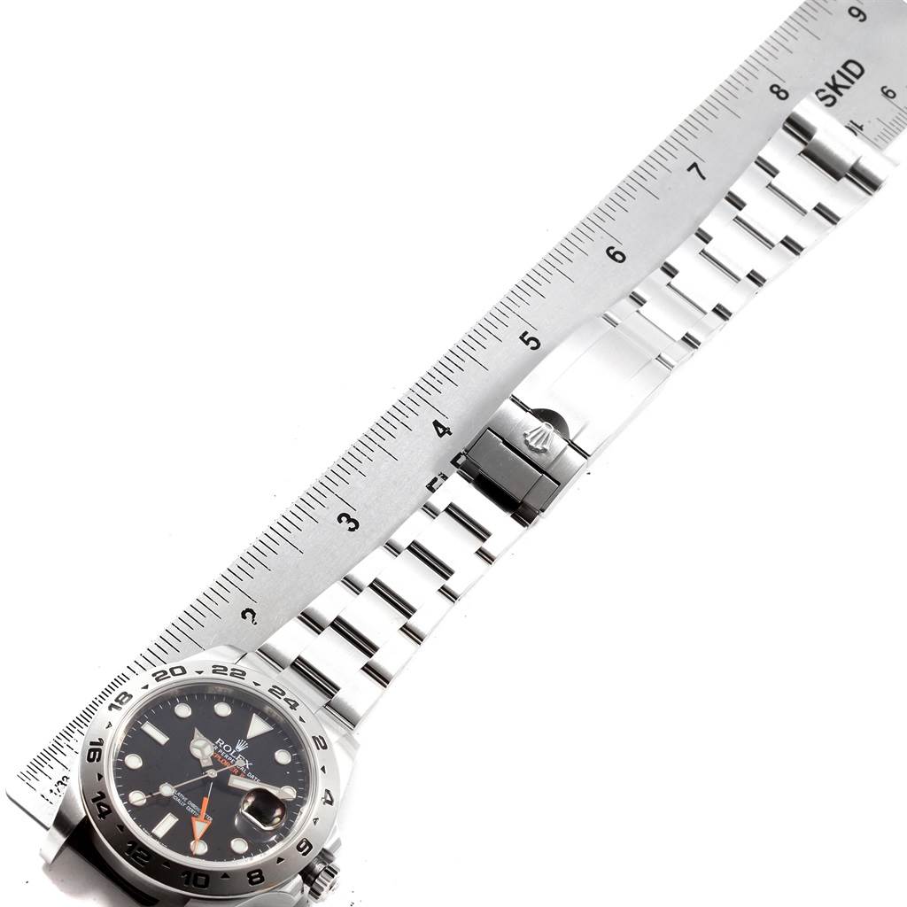 This image shows a side view of a Rolex Explorer 216570 Men's Stainless Steel Black Dial 216570 Men's Stainless Steel Black Dial watch with its full bracelet extended alongside a ruler.