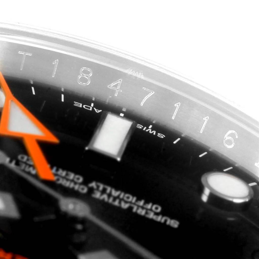 This close-up image shows the dial, orange hour hand, and part of the bezel with engraved numbers of a Rolex Explorer 216570 Men's Stainless Steel Black Dial 216570 Men's Stainless Steel Black Dial watch.