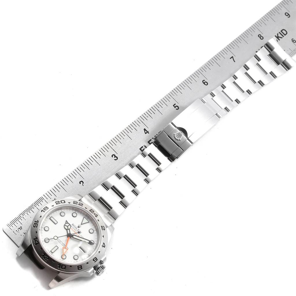 The image shows a top-down view of a Rolex Explorer 216570 Men's Stainless Steel White Dial 216570 Men's Stainless Steel White Dial watch with its band alongside a ruler for measurement.