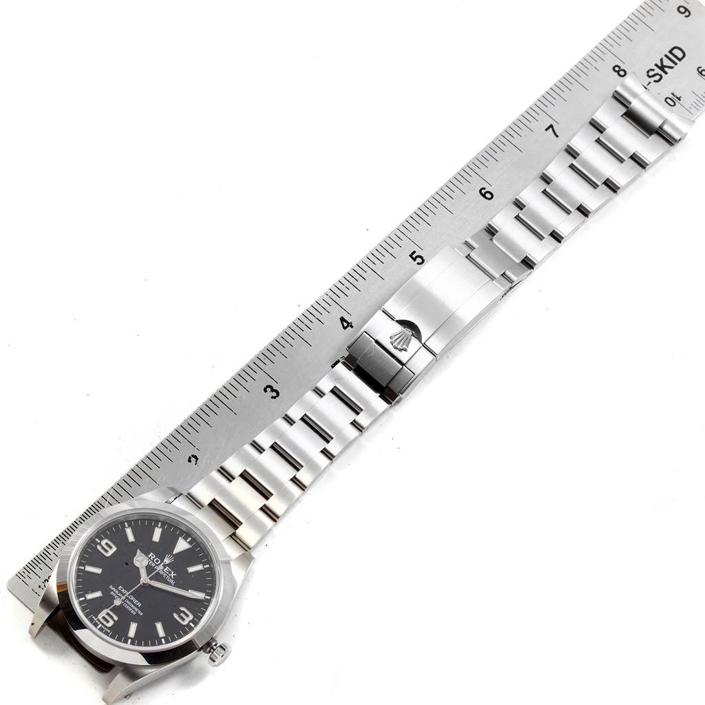 The image shows a top-down view of a Rolex Explorer 214270 Men's Stainless Steel Black Dial 214270 Men's Stainless Steel Black Dial watch with its band aligned next to a ruler.