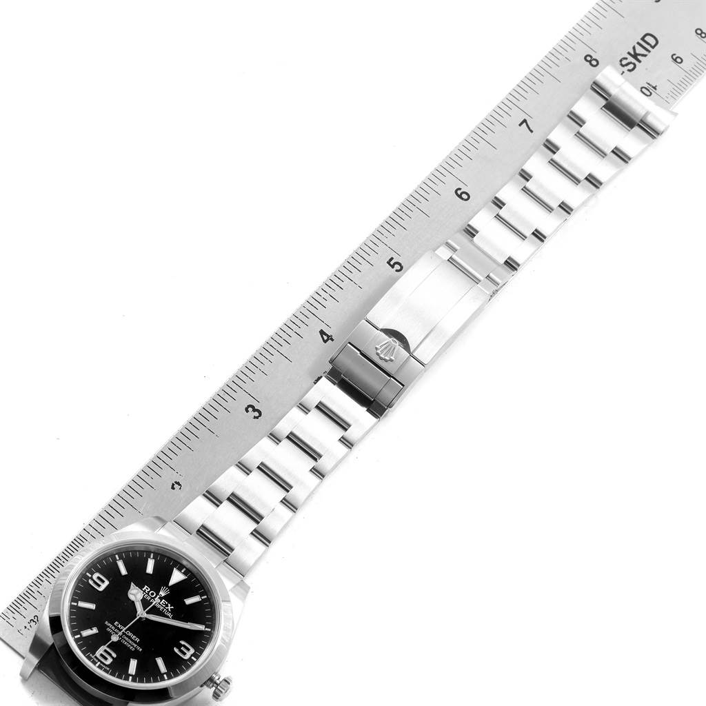 The image shows the face and bracelet of a Rolex Explorer 214270 Men
s Stainless Steel Black Dial 214270 Men
s Stainless Steel Black Dial watch, laid alongside a ruler for scale.